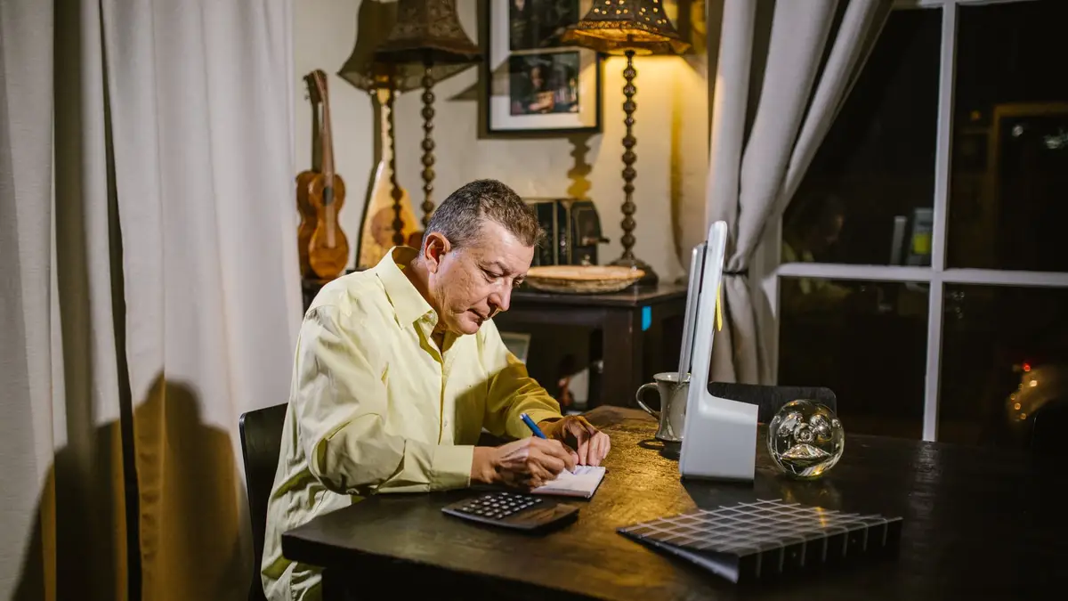 Senior man working out numbers with a calculator at his desk