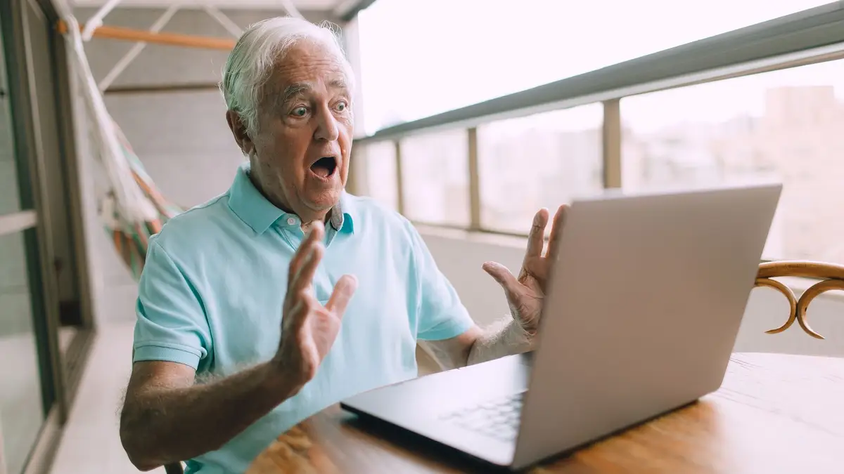 Senior man filling in an online form on his laptop