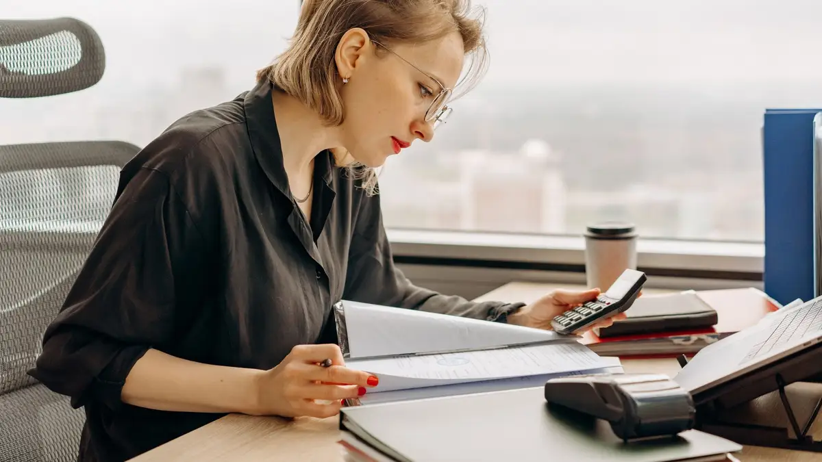 Mature woman at a desk with paperwork and a calculator