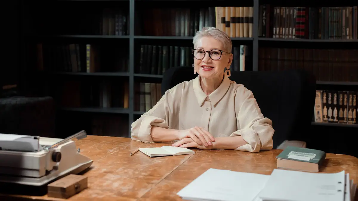 Senior teacher surrounded by books in a library