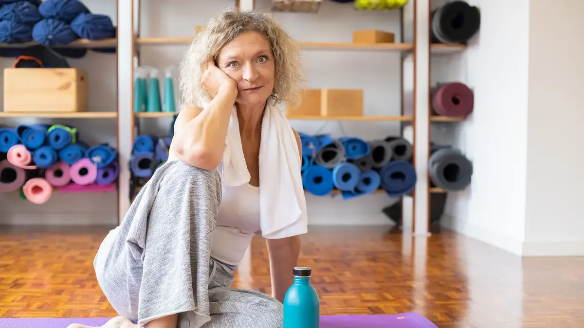 Senior woman doing yoga on a mat at home