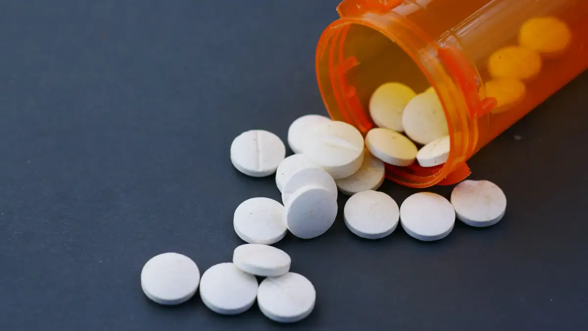 Prescription pills spilling from an orange pharmacy bottle