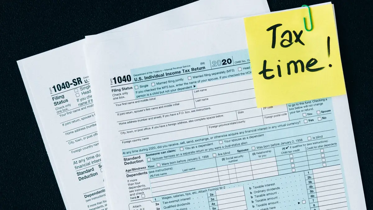 Tax forms on a desk with a sticky note