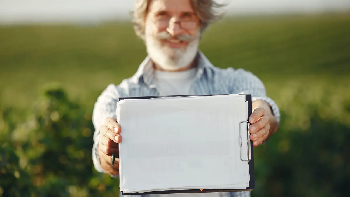 Smiling older man holding up a tablet outdoors