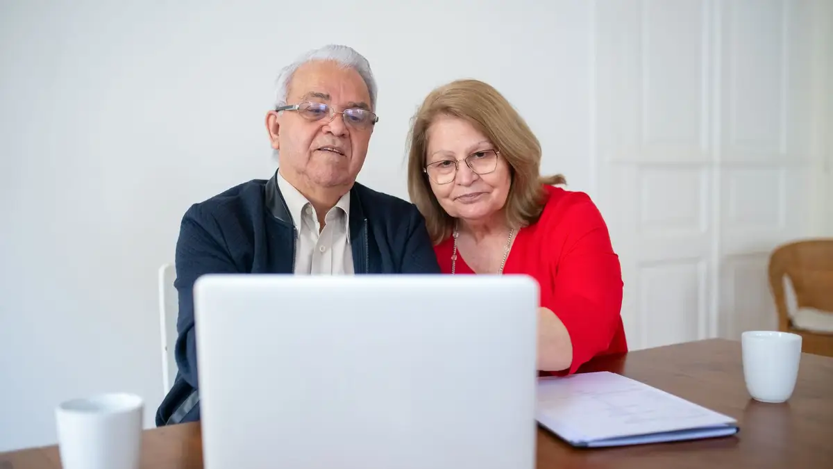 Senior husband and wife looking at a laptop together at home