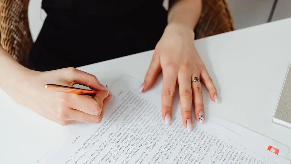 Close-up of a hand signing a document with a pen