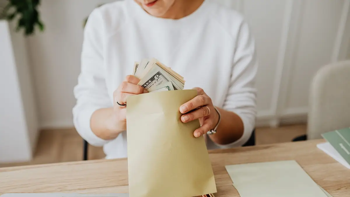 Senior woman counting cash into an envelope