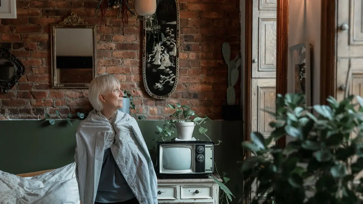 Older woman sitting by a window, looking out thoughtfully
